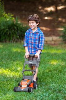 Un bambino che utilizza un tagliaerba in un giardino.