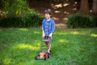 A child using a lawn mower in a garden setting.