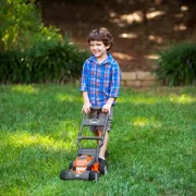 A child using a lawn mower in a garden setting.