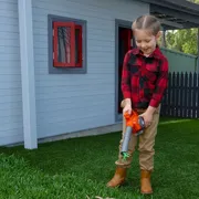 A child using a leaf blower to clear leaves from a lawn in a residential backyard.