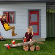 Two children playing in a garden with toy lawn mowers and logs.