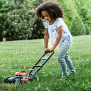 A child mowing the lawn with a push mower in a garden setting.