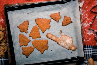 Ein Backblech mit Plätzchen in Form eines Weihnachtsbaums und einem Keks in Nudelholzform.