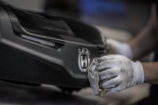 Eine Person, die ein Gerät mit dem Husqvarna-Logo mit einem Tuch reinigt.