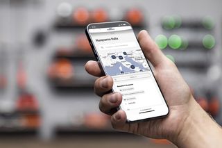 Una persona con in mano uno smartphone che mostra il sito Web di Husqvarna Italia con un'interfaccia mappa.