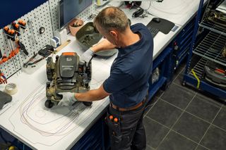 En person som arbetar med en robotgräsklippare i en verkstadsmiljö.