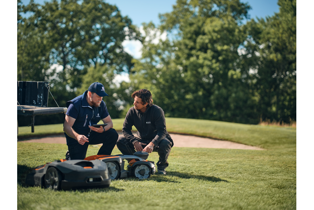 Due persone che ispezionano i robot tagliaerba su un campo da golf.
