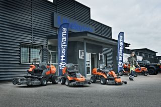 A lineup of Husqvarna ride-on mowers displayed outside a showroom.