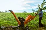 Uma pessoa a utilizar um picador de madeira Husqvarna num ambiente exterior relvado.