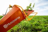 Um carrinho de mão Husqvarna cheio de plantas num campo relvado.