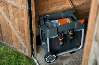 Eine Husqvarna Aufbewahrungsbox mit Rädern in einem Holzschuppen.