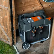 Eine Husqvarna Aufbewahrungsbox mit Rädern in einem Holzschuppen.