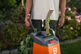 Eine Person, die einen Gartenhäcksler verwendet, um Äste in einer Gartenumgebung zu verarbeiten.