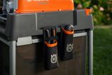 Husqvarna GS 3400s mit angebrachten Werkzeugtaschen in einer Gartenumgebung.