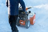 Une personne qui utilise une souffleuse à neige sur une surface enneigée.