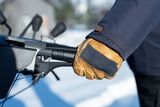 Gros plan d’une personne portant des gants, tenant le guidon d’une souffleuse à neige.