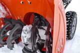 Gros plan de la tarière et de la roue d’une souffleuse à neige recouvertes de neige.