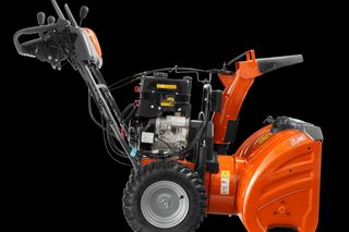 Side view of a snow blower with visible engine and control handles.