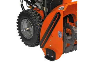 Close-up view of a Husqvarna snow blower attachment with visible auger and tire.