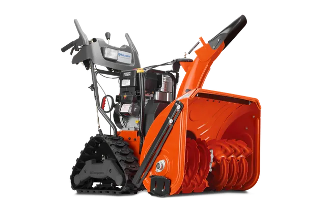 HUSQVARNA 1830EXLT. Side view of a Husqvarna snow blower with visible auger and track drive system.