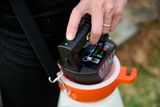 A person placing a battery into a garden sprayer.