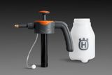 Вид збоку на розпилювальну насадку Husqvarna з приєднаним шлангом та окремою ємністю.