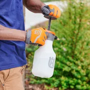 Une personne utilisant un pulvérisateur à pompe manuelle dans un jardin.