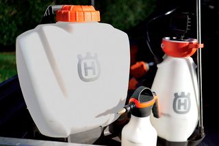 A set of Husqvarna sprayers and containers in a garden setting.
