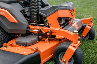 Close-up view of a commercial front mower with visible cutting deck and wheels on grass.
