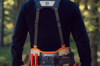 Людина в лісі обличчям у робочому спорядженні Husqvarna з інструментами.