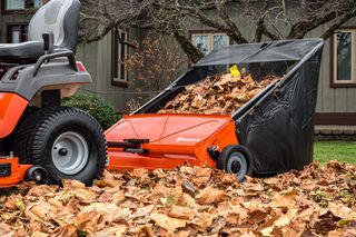 42" Lawn Sweeper. A lawn sweeper collecting fallen leaves in a garden setting.