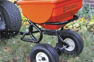 Husqvarna aizmugures izkliedētājs, kas piestiprināts pie zāliena traktora uz zāles.