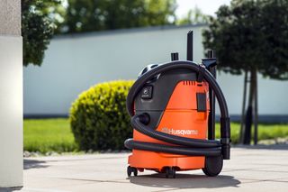 Husqvarna vacuum cleaner with hose attachment on a patio.