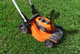 A lawn mower with visible battery compartments on a grassy lawn.