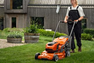A person mowing lawn with a ride-on mower in a garden setting.