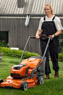 A person mowing lawn with a ride-on mower in a garden setting.