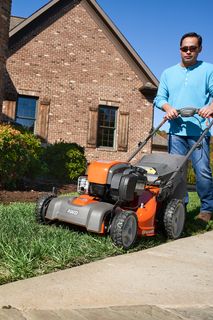 A person mowing lawn with a ride-on mower in a residential garden.
