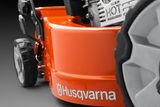 Close-up de um corta-relva Husqvarna mostrando os detalhes da roda e do motor.