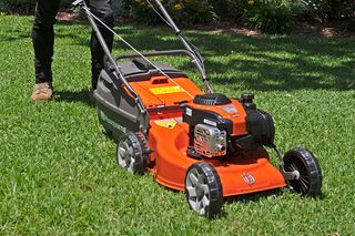 A person using a lawn mower on a grassy lawn.