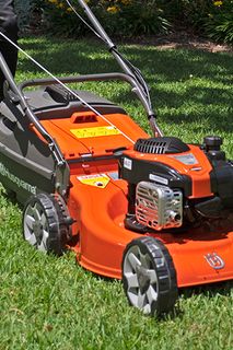 A person using a lawn mower on a grassy lawn.