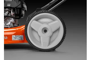 Vista de cerca de la rueda de un cortacésped Husqvarna y parte del motor.