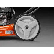 Vista de cerca de la rueda de un cortacésped Husqvarna y parte del motor.
