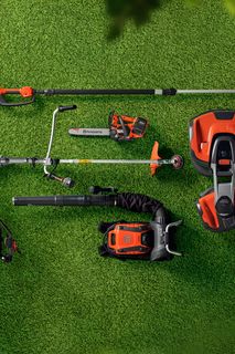 Top view of various gardening tools and equipment arranged on a grass surface.
