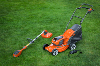 Une tondeuse et un coupe-bordures à fil sur une pelouse présentant des outils d’entretien du jardin.