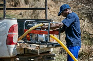 A person loading a portable generator onto a vehicle in an outdoor setting.
