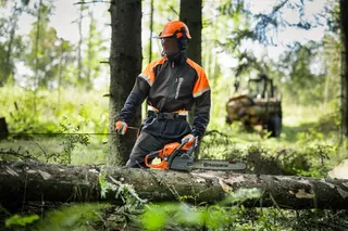 Man i skogen med en motorsåg