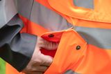 Close-up of a person fastening a button on a bright work jacket.
