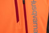 Närbild på en orange arbetsjacka från Husqvarna med dragkedja.