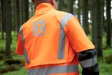Person wearing high-visibility work gear with Husqvarna logo in a forest.