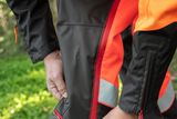 A person adjusting their work trousers in a forest setting.